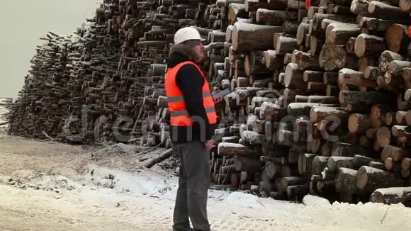 冬季使用平板电脑接近成堆原木的工程师视频的预览图