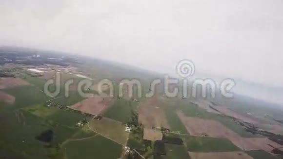 专业跳伞员跳伞在灰色的沉重天空以上的绿色平原体育运动视频的预览图