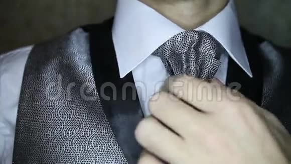 新郎在深色银色领带上矫正胸针视频的预览图