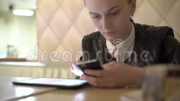 在咖啡馆里用平板电脑和手机关闭女孩4K视频的预览图