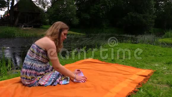 孕妇坐在河边的格子呢和弯曲的纸船上视频的预览图