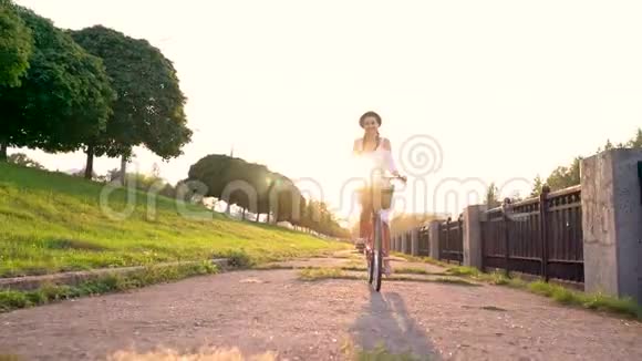 日落时骑自行车的年轻美女慢动作视频的预览图