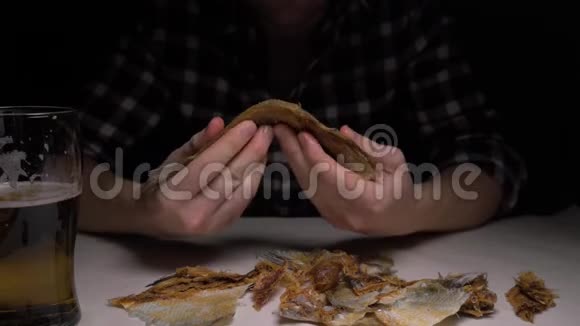 特写镜头雄性手在晚上清洗咸干鱼一个晚上吃鱼喝啤酒的男人4K视频的预览图