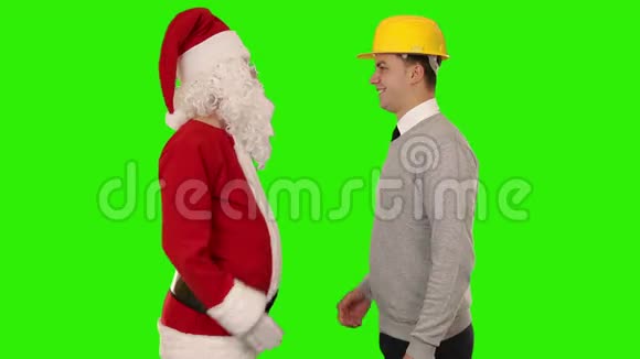圣诞老人和年轻建筑师握手看着相机绿色屏幕股票镜头视频的预览图