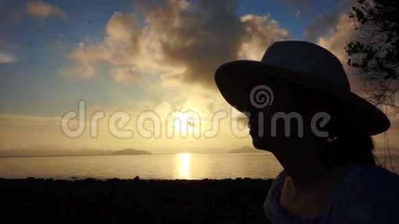 视频亚洲女孩戴着帽子轻松度假黄金日出海洋海滩视频的预览图