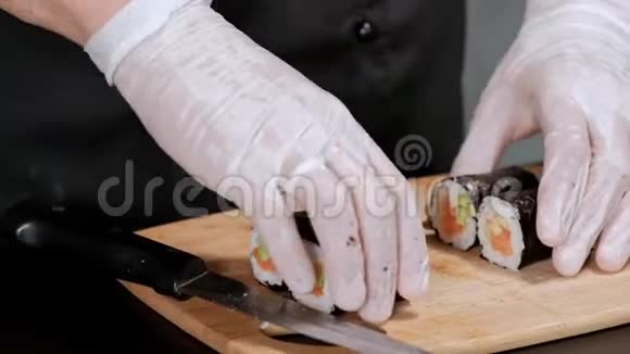 年轻的男性寿司厨师准备日本寿司卷的米饭鲑鱼鳄梨和诺里餐厅厨房特写手视频的预览图