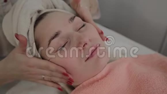 一位专业的美容师在敷面膜之前做面部按摩美容学的新概念视频的预览图