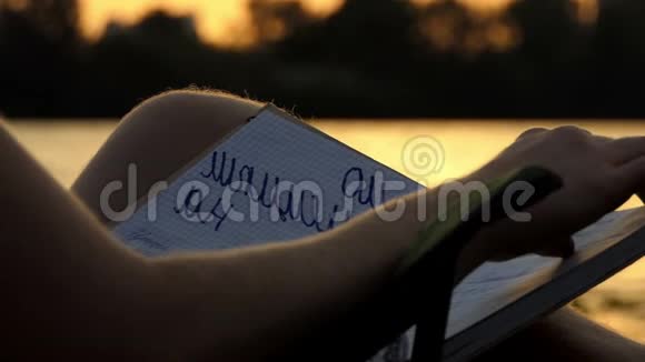 年轻人坐在日落时河岸边的折叠椅上在斯隆莫读书视频的预览图
