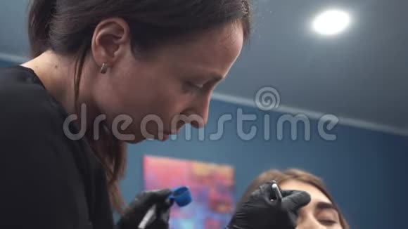 眉毛染色大师用指甲花画眉毛给一个漂亮的女孩用画笔在一个视频的预览图