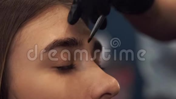 眉毛染色大师用指甲花画眉毛给一个漂亮的女孩用画笔在一个视频的预览图