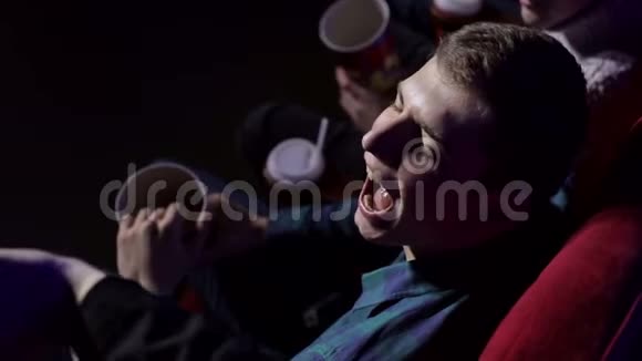一个年轻人在电影院吃爆米花的特写镜头视频的预览图