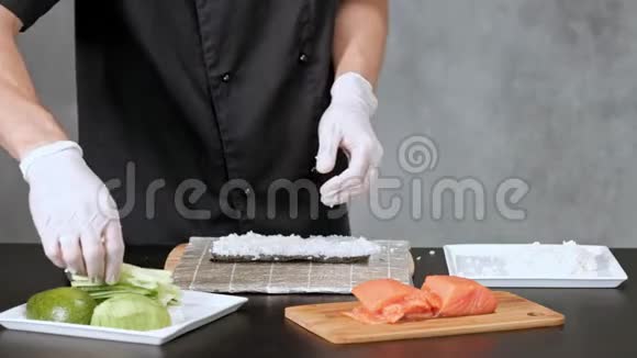 年轻的男性寿司厨师准备日本寿司卷的米饭鲑鱼鳄梨和诺里餐厅厨房视频的预览图