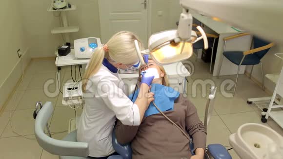 牙医在诊所里治疗年轻妇女的牙齿视频的预览图