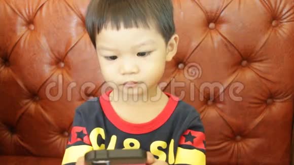 亚洲男孩玩智能手机视频的预览图