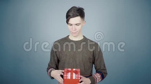 年轻人打开礼物盒惊喜地拿出一顶圣诞老人的帽子视频的预览图