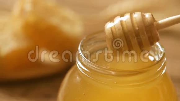 木制背景上装有蜂蜜的罐子里的蜂蜜视频的预览图