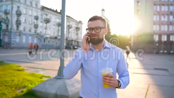 男人在智能手机上说话在街上喝果汁视频的预览图