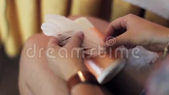 女人的手把白色的笔粘在大蜡烛上膝盖上有橙色的丝带视频的预览图