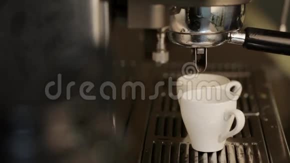 咖啡机将热咖啡倒入两个白色杯子中视频的预览图