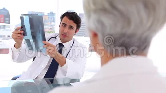 严肃的医生在病人面前拿着X光视频的预览图