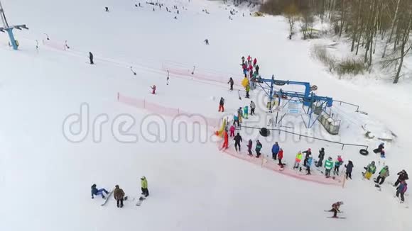 等待滑雪电梯将他们载上雪坡的一群滑雪者和滑雪板者的天线视频的预览图