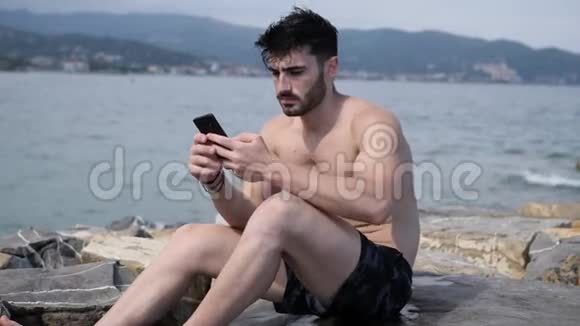 海滩上的年轻人用手机拍海视频的预览图