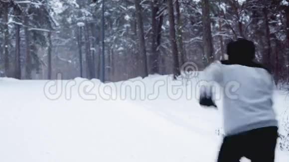 在白雪覆盖的冬天森林道路上奔跑的人视频的预览图