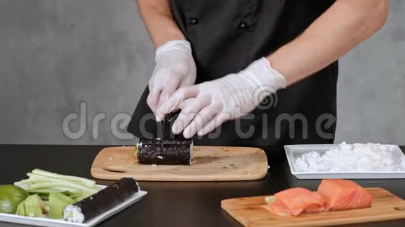 年轻的男性寿司厨师准备日本寿司卷的米饭鲑鱼鳄梨和诺里餐厅厨房特写手视频的预览图