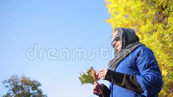 秋天公园戴太阳镜的漂亮女人黄叶视频的预览图