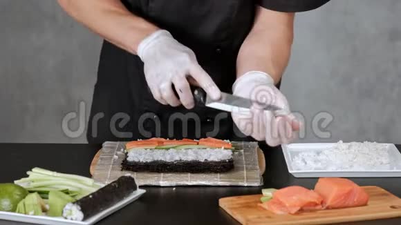年轻的男性寿司厨师准备日本寿司卷的米饭鲑鱼鳄梨和诺里餐厅厨房视频的预览图