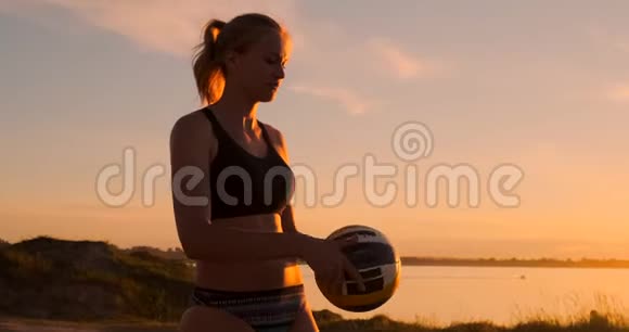 在一个美丽的夏日傍晚运动女孩在沙滩排球比赛中跳到空中在网上击球视频的预览图