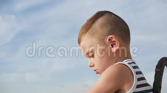可爱的小男孩在天空背景上穿着水手条纹衬衫视频的预览图