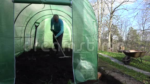 农民用耙子工具在温室里平整土壤4K视频的预览图