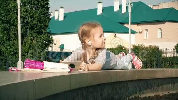 美丽的女孩在喷泉附近用手机耳机听音乐视频的预览图