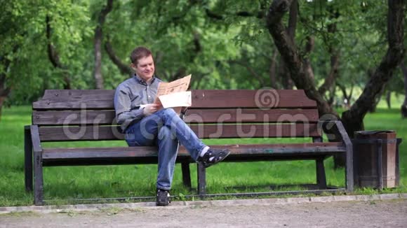 人在公园的长凳上看报纸视频的预览图