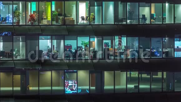 晚上在玻璃办公楼工作有许多办公室有玻璃墙和窗户时间推移视频的预览图