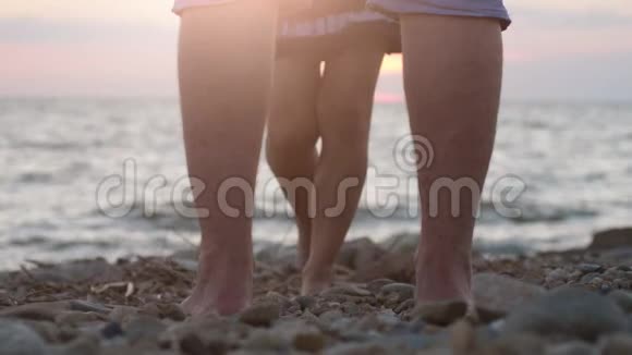 在美丽的日落中一对情侣的腿在海滩上靠近大海男人举起手来她心爱的女人视频的预览图