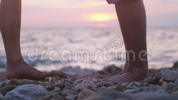 在美丽的日落时在海边的海边约会时一对情侣的腿男人举起手来视频的预览图