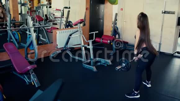 年轻漂亮的女孩长发在健身房做运动用杠铃在蹲视频的预览图