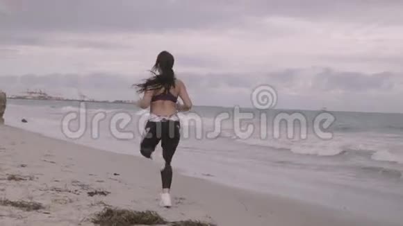 年轻健康的运动女人在海滩上跑步超级慢动作稳定器射击视频的预览图