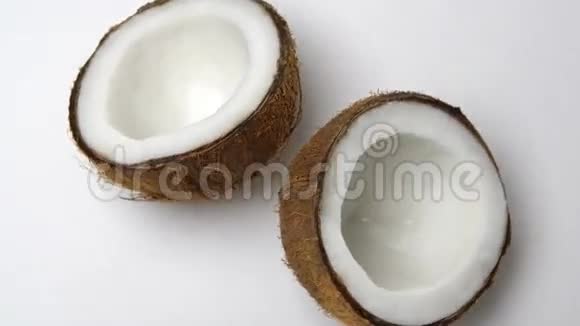 成熟的热带椰子分成两半在白色背景下旋转热带水果可循环视频的预览图