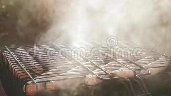 在烧烤架上烤香肠将猪肉香肠烤在带有香肠的便携式烤架上靠近烤架肉视频的预览图