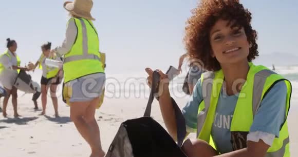 女志愿者在阳光明媚的4k天清洁海滩视频的预览图