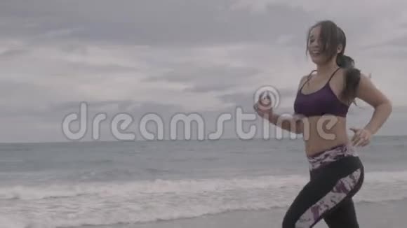 年轻健康的运动女人在海滩上跑步超级慢动作稳定器射击视频的预览图