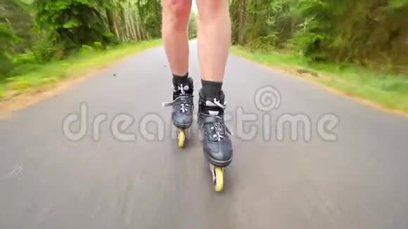 在松林的路上滑着滑溜在炎热的夏天曼斯腿在沥青上轮滑快速洗牌视频的预览图