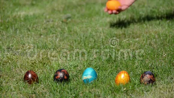 手把五颜六色的鸡蛋扔在草地上传统复活节游戏视频的预览图