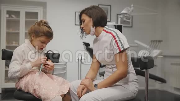牙医给一个小女孩做咨询让她知道如何用假牙刷牙特写视频的预览图