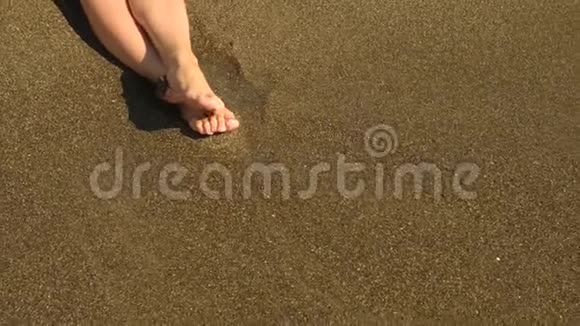 向下移动关闭年轻的女性长腿在海滩上行走并将海水喷洒到相机中4k视频的预览图