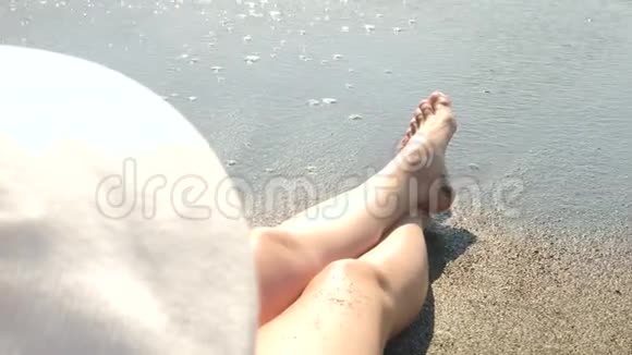 向下移动关闭年轻的女性长腿在海滩上行走并将海水喷洒到相机中4k视频的预览图