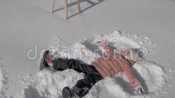 美丽的小女孩做雪天使视频的预览图